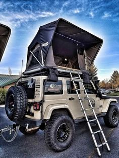 an off road vehicle parked in a parking lot with its roof open and ladder up