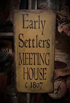 a sign that says early settlers meeting house c 1897 in front of many other items