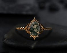 a gold ring with a green stone in the center on top of a black surface