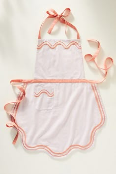 a pink apron with an orange ribbon tied around it