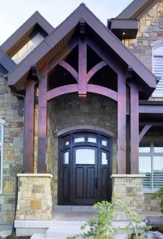 the front entrance to a home with stone pillars and arched windows, along with a wooden door