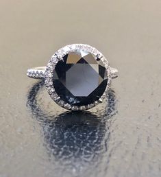 DeKara Designs Collection Metal- 95% Platinum, 5% Iridium. Stones- Genuine Round Black Diamond 6.50 Carats 10.25 MM, 44 Round Diamonds F-G Color VS1-VS2 Clarity 0.28 Carats. Size- 5 3/4. FREE SIZING Beautiful Handmade Platinum Halo Black Diamond Engagement Ring. The beautiful and fiery round black diamond is uniquely cut and is professionally set in between four Eagle Claw prongs. The center black diamond is surrounded by 24 round dazzling diamonds that are meticulously French Pave set, as well Classic Black Sapphire Ring With Prong Setting, Black Diamond Ring With Halo Setting For Anniversary, Timeless Black Jewelry With Center Stone, Formal Black Round Cut Rings, Classic Black Diamond Ring For Wedding, Formal Black Diamond Ring With Prong Setting, Elegant Black Sapphire Ring With Center Stone, Formal Black Sapphire Ring With Center Stone, Classic Black Diamond Ring With Brilliant Cut