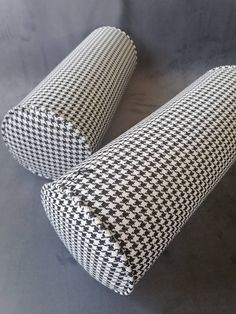 two black and white pillows sitting on top of each other in front of a gray background