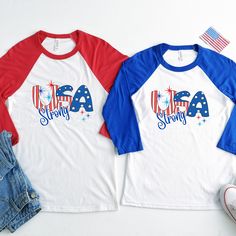 two red, white and blue shirts with the word usa strong on them next to a pair of jeans