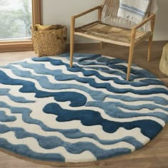 a blue and white rug with waves on it in front of a chair next to a window