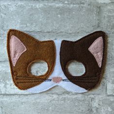 a cat mask hanging on a brick wall with two holes in the front and one hole in the back