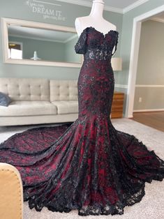 a black and red dress on display in a room with a couch, chair and mirror