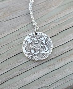 "This is an adorable circle pendant that has daisies and leaves stamped on it. It is silver plated and measures just over 3/4\". *Choose your necklace length that check out. The chain is stainless steel.  This will be sent to you in a gift box. This is perfect for anyone! Birthdays, anniversaries, jewelry for bridesmaids, gifts for Mom, or any other occasion. Please contact me if you have any custom requests or questions. Shipping is typically 4 to 6 days in the US, Or you can upgrade to Priority (2 to 3 days) or Express (1 to 2 days). International shipping is between 1 to 3 weeks, depending on your location. You can select an upgrade at checkout." Silver Charm Necklace With Birth Flower Round Pendant, Silver Medallion Necklace With Flower Charm, Silver Birth Flower Round Pendant Charm Necklace, Silver Medallion Necklace With Birth Flower, Silver Charm Necklace With Flower Charm, Silver Charm Necklace With Round Flower Charm, Silver Flower Charm Necklace With Round Pendant, Silver Flower Necklace For Mother's Day, Mother's Day Silver Flower Necklace With Round Pendant