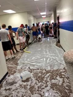 a group of people standing in a hallway with plastic covering the floor and one person holding a water bottle