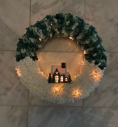 a wreath with lights around it and a house in the middle on top of marble tiles