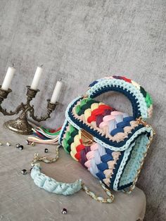 a purse sitting on top of a table next to a candelabra and two candles