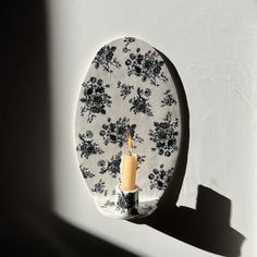 a candle is lit on a plate with a flower pattern and black trim around it