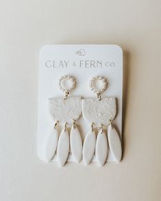 three pairs of white ceramic earrings with pearls on the bottom and one earring in the middle