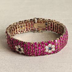 This gorgeous bracelet mimics an 18k gold ruby, sapphire, and diamond bracelet.   It is gold-plated (vermeil) sterling silver with ruby-colored, sapphire-colored, and clear glass (CZ) stones.  The craftsmanship is excellent--each stone is faceted and prong-set.  It has a hidden clasp with safety clasps on either side of the main clasp.  The bracelet is approximately 7 1/4 inches long and 5/8 inches wide.  Weight is 56 g.  In very good condition with no missing stones.   Note:  Vintage jewelry is Luxury Red Pink Sapphire Jewelry, Formal Pink Ruby Bracelets, Formal Pink Ruby Bracelet, Elegant Multi-stone Pink Sapphire Jewelry, Elegant Pink Sapphire Multi-stone Jewelry, Gold Jewelry With Multi-stone Pink Sapphire, Gold Multi-stone Pink Sapphire Jewelry, Gold Multi-stone Jewelry With Pink Sapphire, Pink Sapphire Multi-stone Gold Jewelry