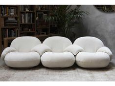 a white couch sitting on top of a floor next to a book shelf