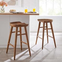 two wooden stools sitting in front of a counter