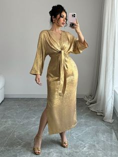 a woman in a gold dress taking a selfie