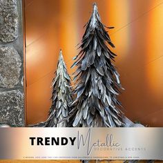 a metal christmas tree sitting on top of a wooden table next to a stone wall