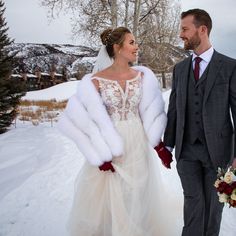 the bride and groom are walking through the snow in their winter wedding attire with fur stolers