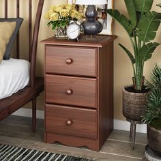 a bedroom scene with focus on the nightstand and flowers in vases next to it