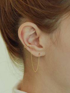 a woman wearing a gold chain ear cuff