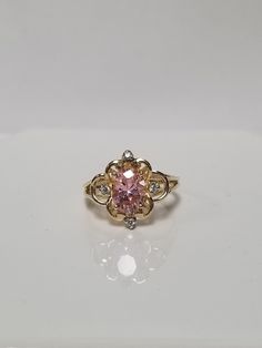 "Thanks for shopping our vintage estate store. We tend to sell well below wholesale and truly hope you enjoy all of our items. Many of the items are one of a kind, so please enjoy scrolling through the pictures and hopefully something will catch your eye. Brown spots are from camera or reflections. Estate 10k yellow gold created pink 1.5ct ice cz diamond filigree cocktail ring.  White gems are cz diamonds also.  Ring size: 5.75 Gem: 8mm by 5mm Setting: 1/2\"  Band Width: 1.5mm Weight: 2.70 grams Sweet ring, one that you will love. Marked 10K." Classic Pink Cluster Ring For Anniversary, Vintage Pink Diamond Ring Hallmarked, Vintage Yellow Gold Cluster Ring With Accent Stones, Vintage Cluster Ring With Accent Stones For Formal Occasions, Vintage Pink Diamond Ring With Hallmark, Vintage 14k Gold Rings With Accent Stones, Vintage 14k Gold Birthstone Ring With Center Stone, Vintage Birthstone Ring With Diamond Accents For Gift, Vintage Birthstone Ring With Diamond Accents As Gift