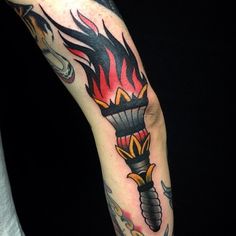 a man with a tattoo on his arm holding a cell phone in one hand and a lighter in the other