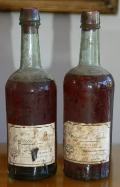 two old bottles sitting on top of a wooden table