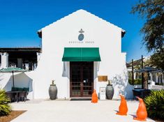 a white building with green awnings and two orange cones in front of it