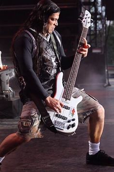 a man with long hair holding a bass guitar in his hand while standing on stage