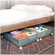 a bed with two baskets underneath it on the floor next to a pillow and some books