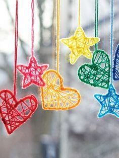 four colorful hearts hanging from strings in front of a window