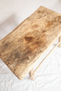 an old wooden table sitting on top of a white sheet