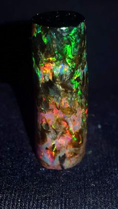 an opalized glass is sitting on the floor in front of a black background