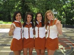 four young women dressed in orange and white posing for the camera with their thumbs up