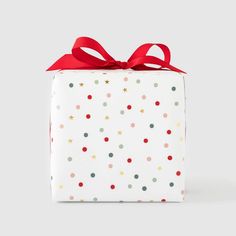 a white gift box with red ribbon and polka dot pattern on the wrapping paper it is wrapped in