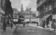 an old black and white photo of people walking down the street in front of buildings