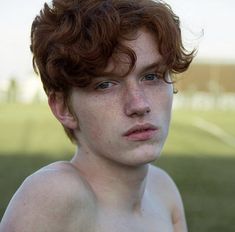 a shirtless young man with frizz on his face looking at the camera