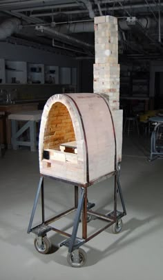 an outdoor oven sitting on top of a dolly in a warehouse area with tables and chairs around it