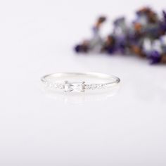 a close up of a ring on a white surface with flowers in the back ground