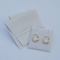 two pairs of small gold hoop earrings sitting on top of a white piece of paper