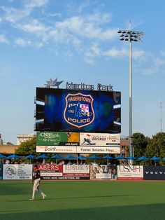 a baseball player walking across a field in front of a large scoreboard with the words marlbow park on it