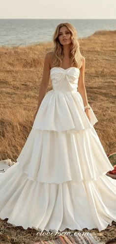 a woman in a wedding dress standing on the beach