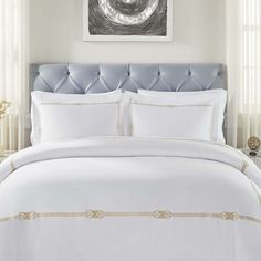 a white bed with gold trimmings in a hotel room or guest room,