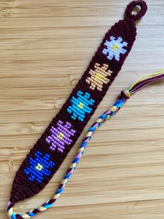 a cross - stitch lanyard with beads and tassels on a wooden surface