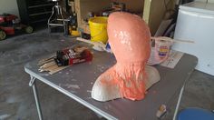 a clay head sitting on top of a table next to paintbrushes and glue