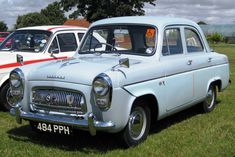 two old cars are parked in the grass