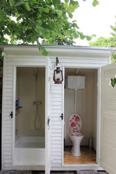 a white toilet sitting inside of a small bathroom next to a shower and sink in a yard