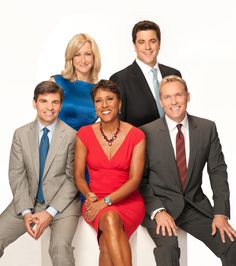 a group of people sitting next to each other on top of a white wall in suits and ties