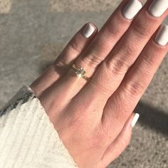 a woman's hand with white nails and a ring